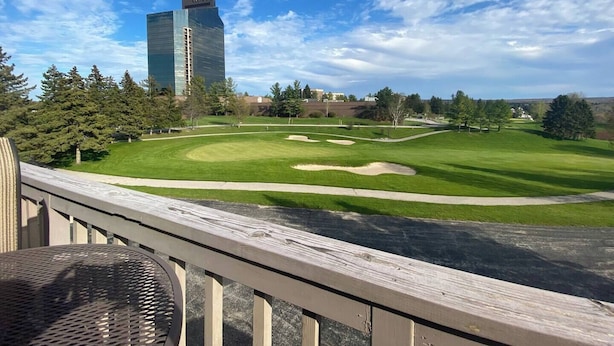 A golf course with a view of a modern building in the background. - Awesome Condo in Acme, Michigan (Williamsburg)