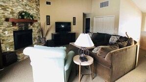 A living room with a stone fireplace, a television, a sofa, and a lamp. - Awesome Condo in Acme, Michigan (Williamsburg)