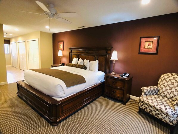 A hotel room with a large bed, a nightstand with a lamp, a chair, and a ceiling fan. - Awesome Condo in Acme, Michigan (Williamsburg)