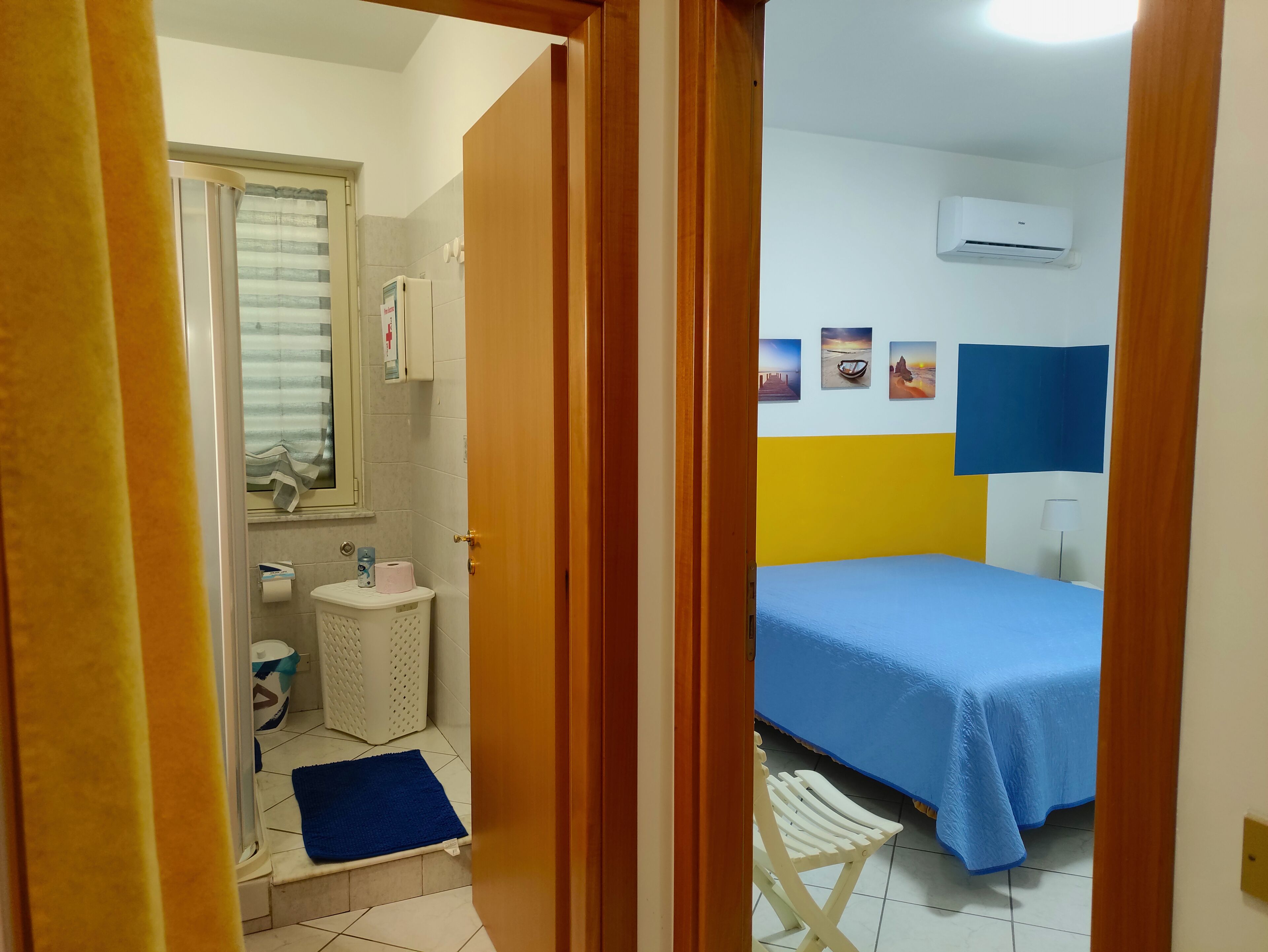 Een kamer met een bed, een kleine badkamer en een raam met zonwering.