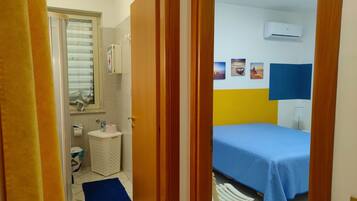 Een kamer met een bed, een kleine badkamer en een raam met zonwering.