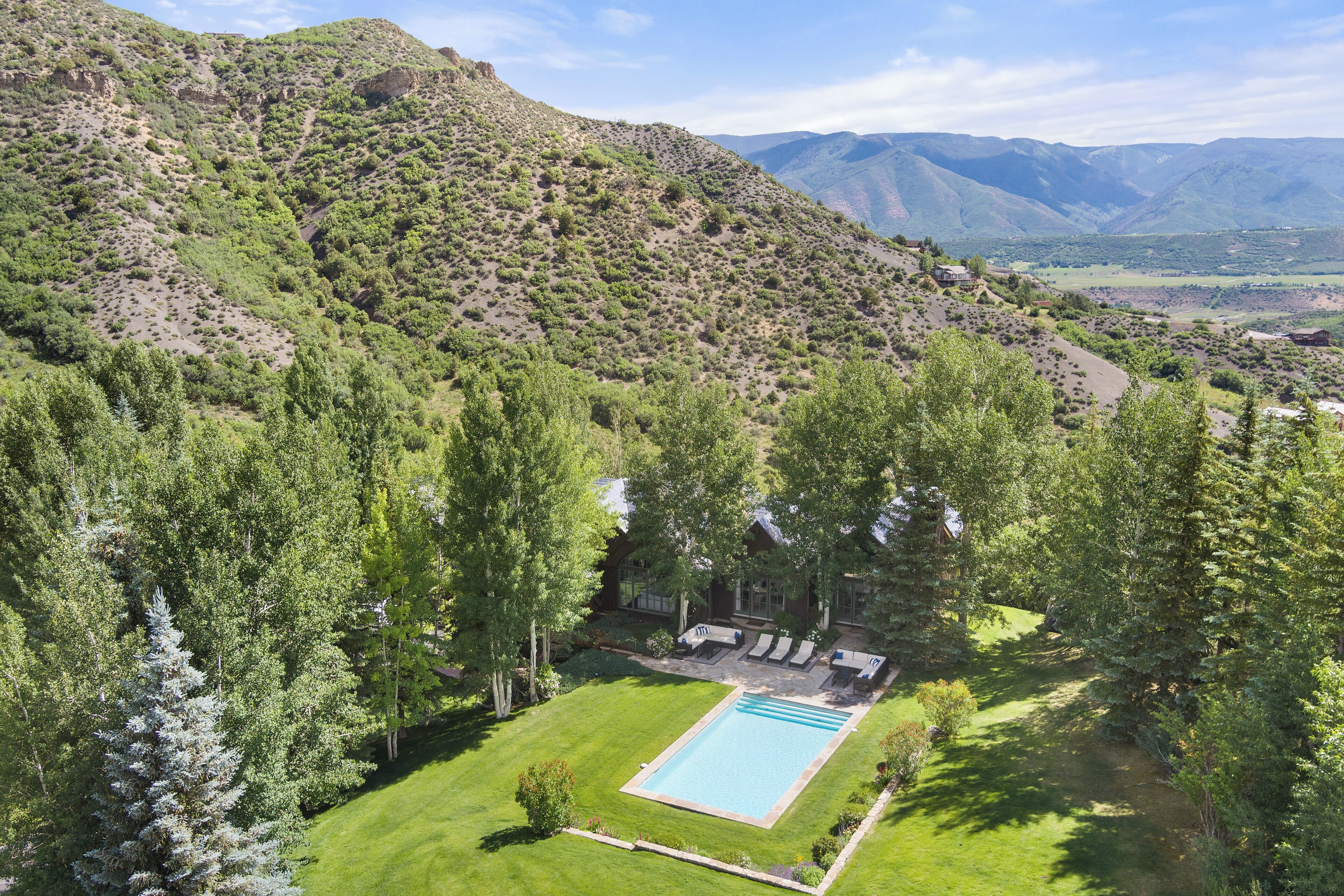 A pool area surrounded by lush greenery and mountains in the background.