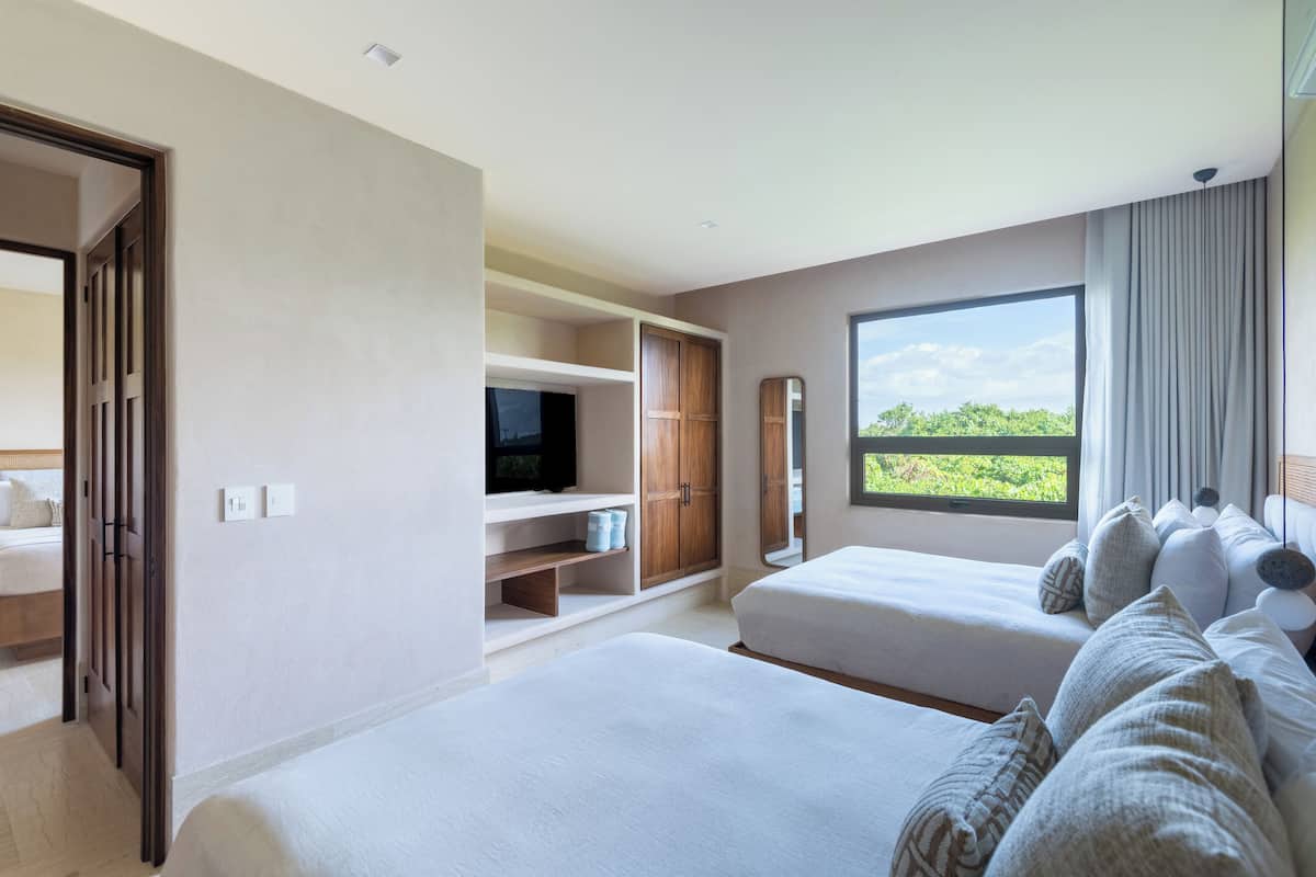 A hotel room with two beds, a TV, a wardrobe, and a large window with a view.