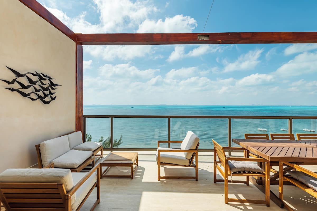 A wooden deck with a wooden table and chairs, a sofa, and a wall art piece.