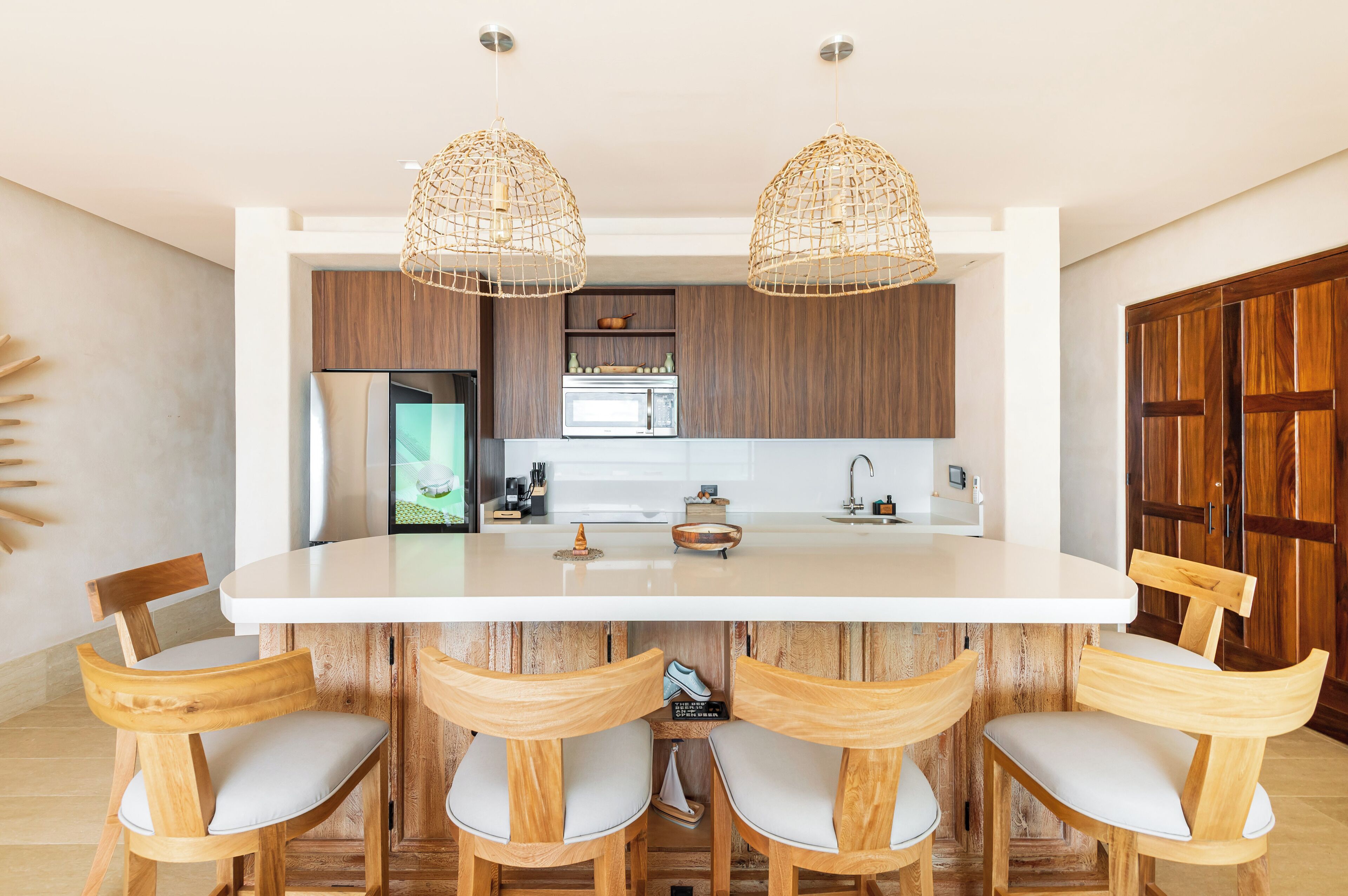 A modern kitchen with wooden cabinets, a central island with bar stools, and pendant lighting.