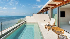 Zona de piscina exterior moderna amb vista despejada a l'oceà, gandules de fusta i una sala amb envidriera.
