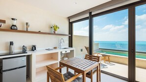 Una cuina moderna amb vista a l'oceà, zona de dinar amb mobiliari de fusta i un petit balcó amb una cadira.