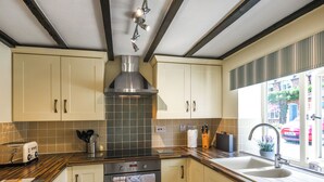 Una cocina moderna con extractor de acero inoxidable, horno empotrado y ventana con vistas a la calle.