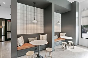Un intérieur moderne avec un espace salon comprenant un banc et des tabourets, une table ronde et des luminaires suspendus.