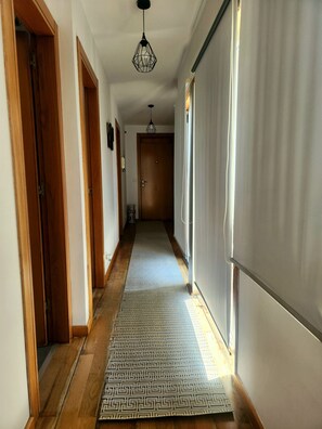 A hallway with wooden doors, a patterned rug, and a ceiling light fixture.