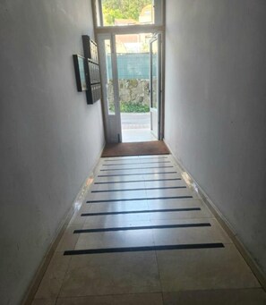 A hallway with a tiled floor and a door leading outside.