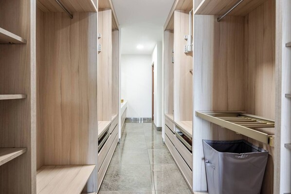 Un couloir étroit, avec des casiers en bois de part et d’autre, une poubelle et un sol carrelé.