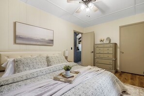 A bedroom with a bed, a dresser, a ceiling fan, and a painting on the wall. - Charming Cabin on Lake Malone – Perfect Getaway! ~Lakefront w/ firepit~ (Lewisburg)