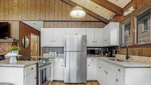 A modern kitchen with white cabinets, stainless steel appliances, and a wooden ceiling. - Charming Cabin on Lake Malone – Perfect Getaway! ~Lakefront w/ firepit~ (Lewisburg)