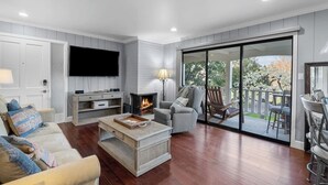 Amplia sala de estar con chimenea, televisor de pantalla plana y puerta corrediza de vidrio que da a un patio exterior.