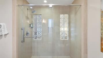 Een douche met glazen wanden, glazen deur, douchekop en een handgreep.