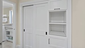 Um armário branco com várias prateleiras e uma porta.