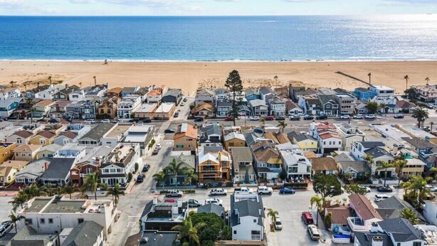 A coastal residential area with houses and a beach in the background.