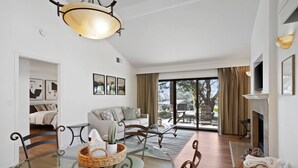 A spacious living room with a glass dining table, a sofa, and a fireplace.