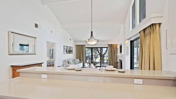 A spacious kitchen with a large island, a dining area with a sofa and chairs, and a view of the outdoors.