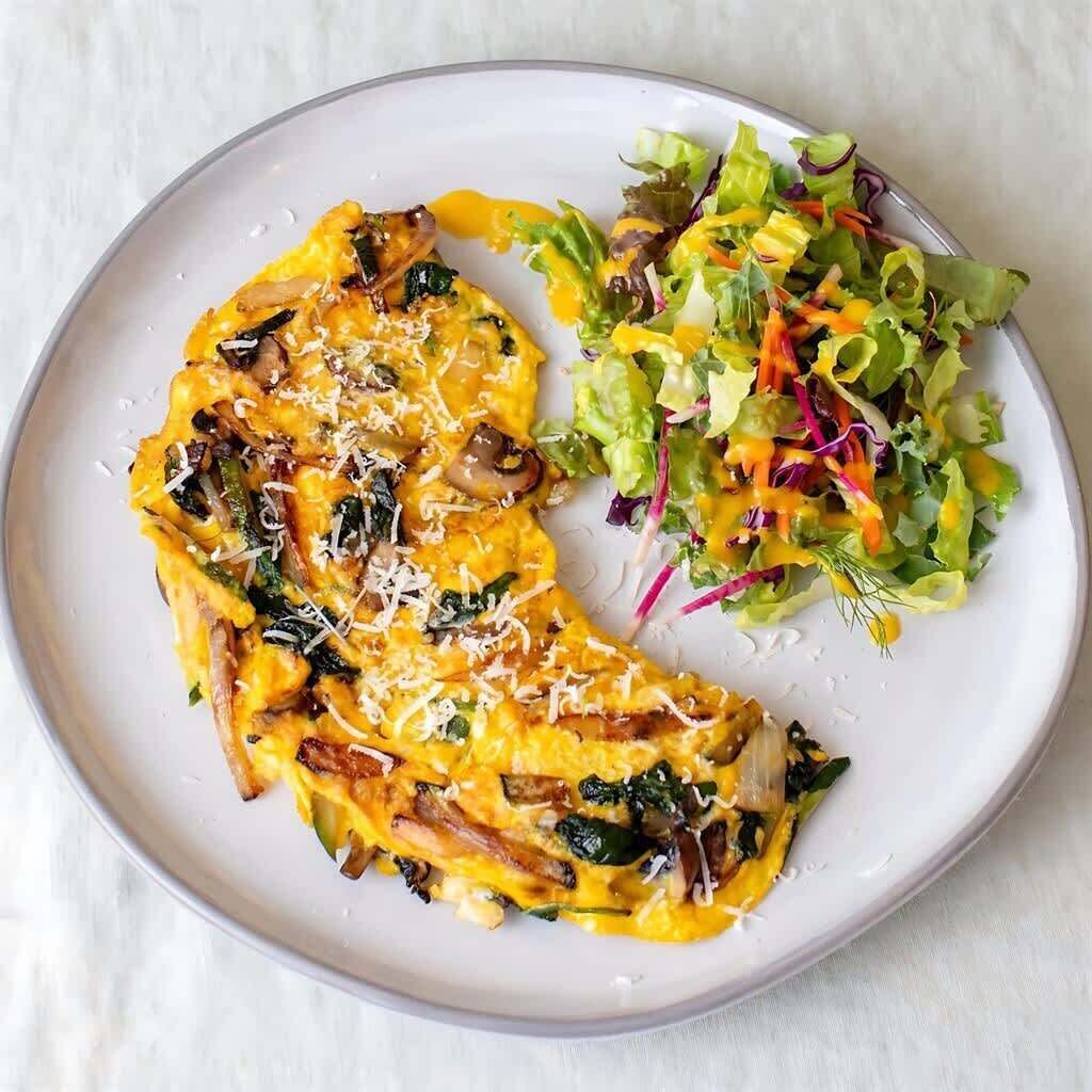 Un plato con una tortilla a la plancha y una ensalada.