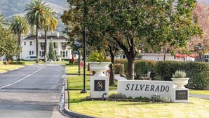 Un panneau de signalisation indiquant la direction de Silverado, avec une route dégagée, des palmiers et un bâtiment en arrière-plan.
