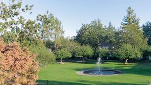 Un parc doté d’une fontaine, d’arbres et d’une pelouse bien entretenue.