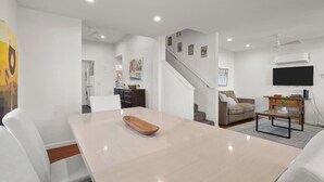 Uma sala de estar moderna com uma mesa de jantar, sofá e escada que leva a outro andar.