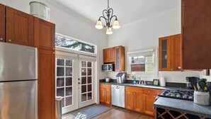 Una cucina con mobili in legno, elettrodomestici in acciaio inossidabile e una cantinetta per vini.