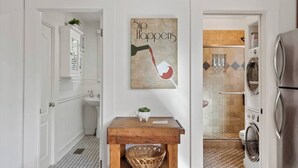 Un bagno con un lavandino, un tavolino in legno con un cesto e un'opera d'arte appesa al muro.