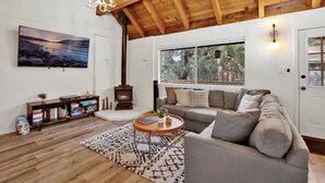 A cozy living room with a wooden ceiling, a fireplace, a sofa, a coffee table, and a bookshelf. - Large Bear Lodge #2488 (Sugarloaf)
