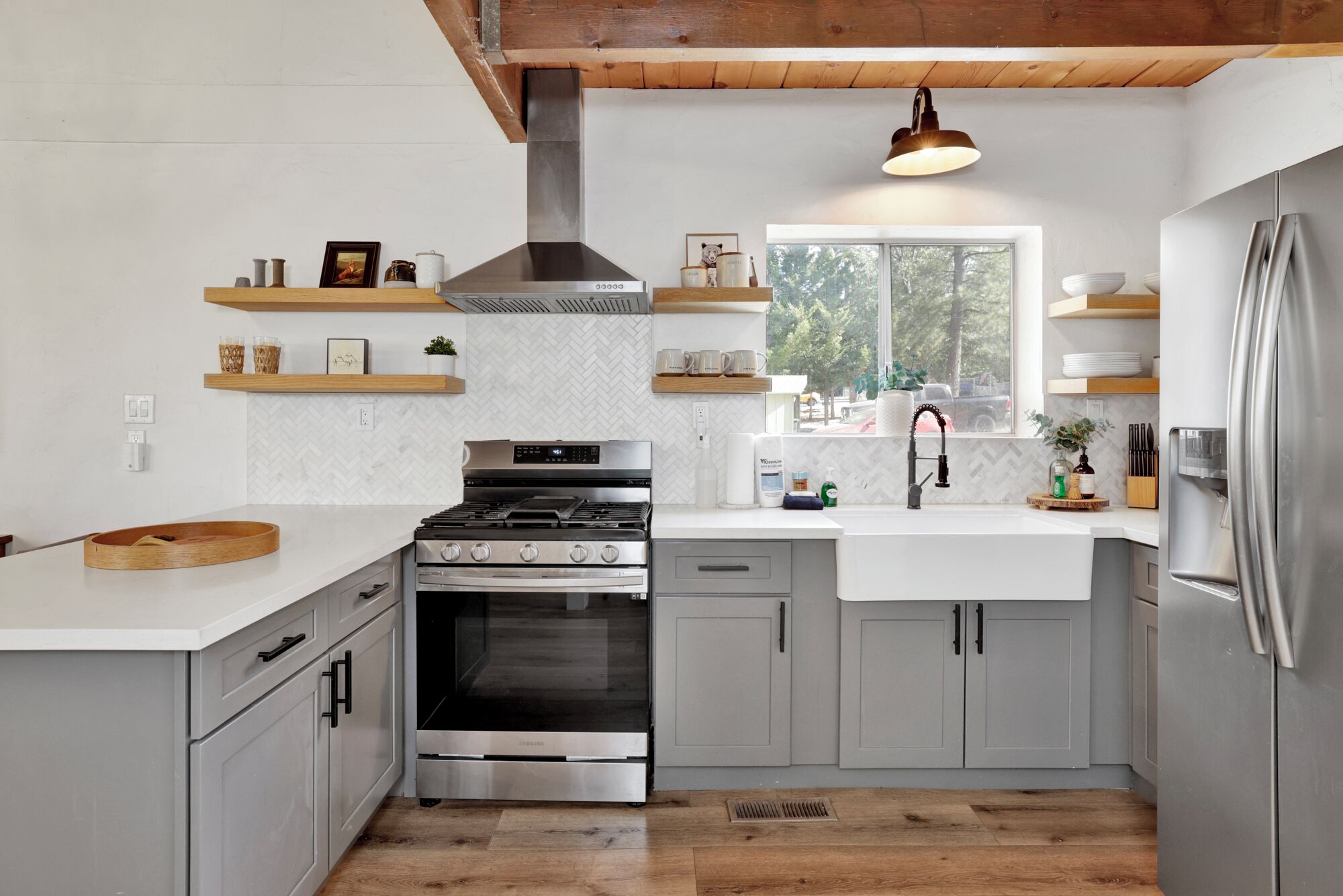A modern kitchen with grey cabinets, stainless steel appliances, and wooden accents.