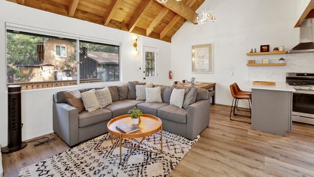 A spacious living area with a gray sectional sofa, a round coffee table, and a kitchen with a modern design. - Large Bear Lodge #2488 (Sugarloaf)