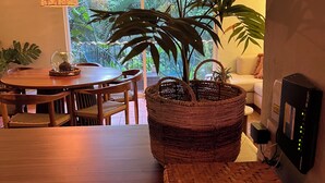 Een gezellig eetgedeelte met een houten tafel en stoelen, een geweven mand met een plant en een hanglamp.