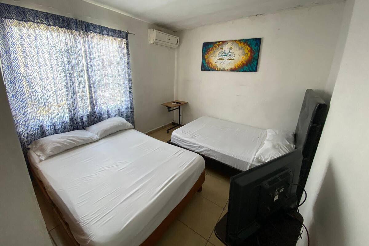 A room with two beds, a television, and a painting on the wall.