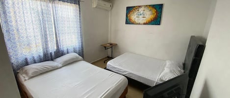 A room with two beds, a television, and a painting on the wall.