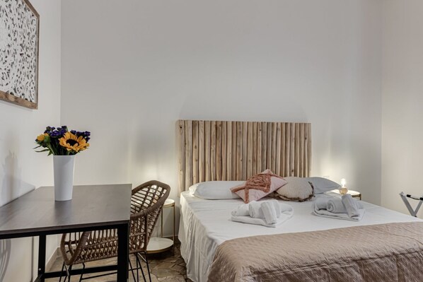 A bedroom with a bed, bedside tables, a chair, and a wall-mounted artwork.