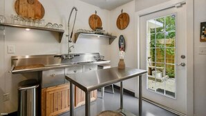 A modern kitchen with stainless steel appliances, wooden cabinets, and a large window offering a view of the outdoors.