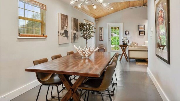 A dining area with a large wooden table, multiple chairs, a chandelier, and artwork on the walls.