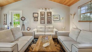 A modern living room with two white sofas, a wooden coffee table, and framed artwork on the wall.