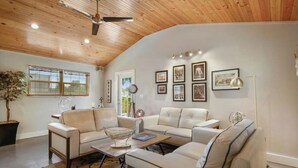 A living room with a wooden ceiling, two sofas, a coffee table, and framed pictures on the wall.
