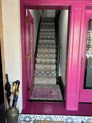 Staircase with a unique zigzag patterned carpet leads to an upper floor, flanked by painted walls and a decorative rug.