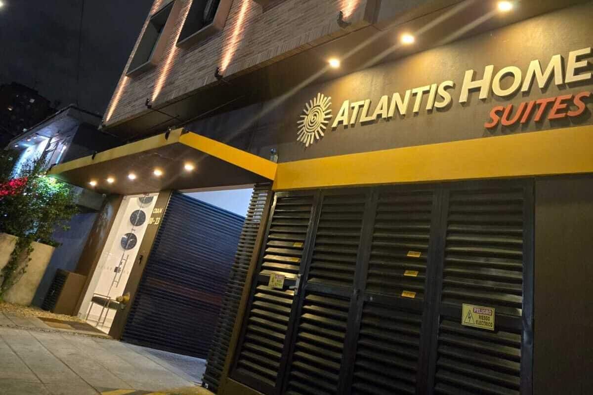 Un edificio con un letrero que dice 'Atlantis Home Suites' de noche.