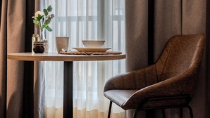 A room with a round table, a brown leather chair, and a window with sheer curtains. - Atlantis Home Zona T (Bogotá)