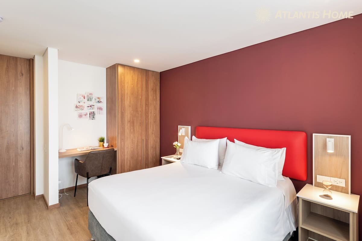 Una habitación de hotel moderna con una cama grande, un escritorio y un armario.