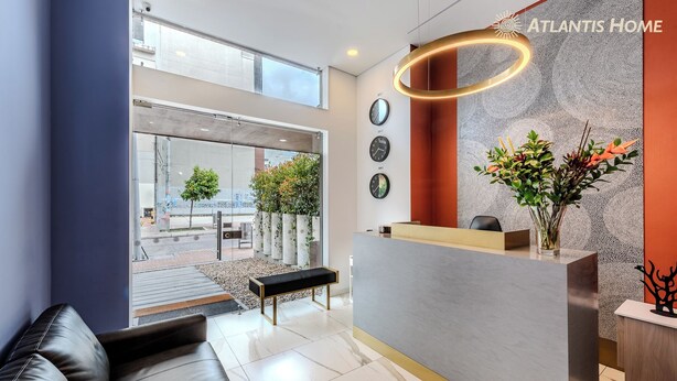 A modern reception area with a glass entrance, a bench, and a reception desk. - Atlantis Home Zona T (Bogotá)