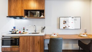 A modern kitchen with wooden cabinets, a built-in oven, and a digital display. - Atlantis Home Zona T (Bogotá)