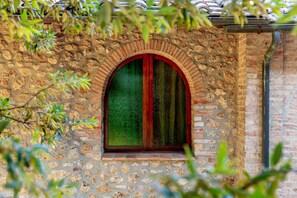 A stone wall with a window featuring a green curtain.