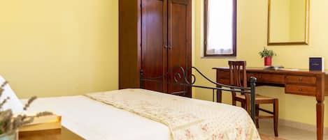 Un dormitorio con cama, un escritorio de madera, un armario y un espejo.