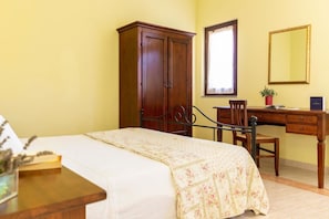 A bedroom with a bed, a wooden desk, a wardrobe, and a mirror.
